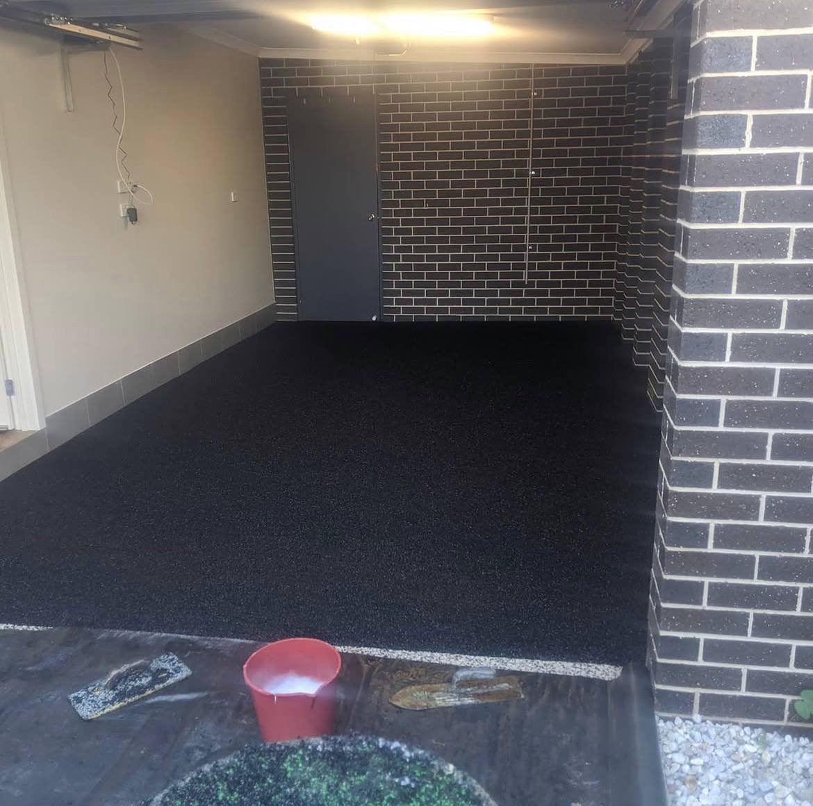Seamless black wet pour rubber floor freshly installed in a residential garage gym in Melbourne