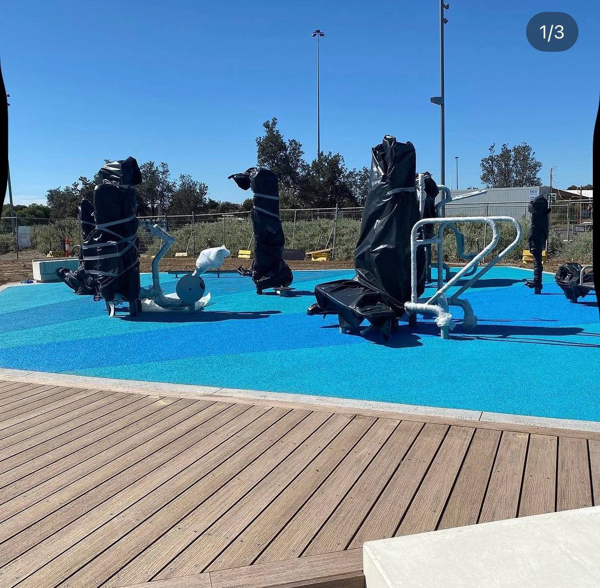 Blue wet pour rubber surfacing around an outdoor fitness area with a timber deck