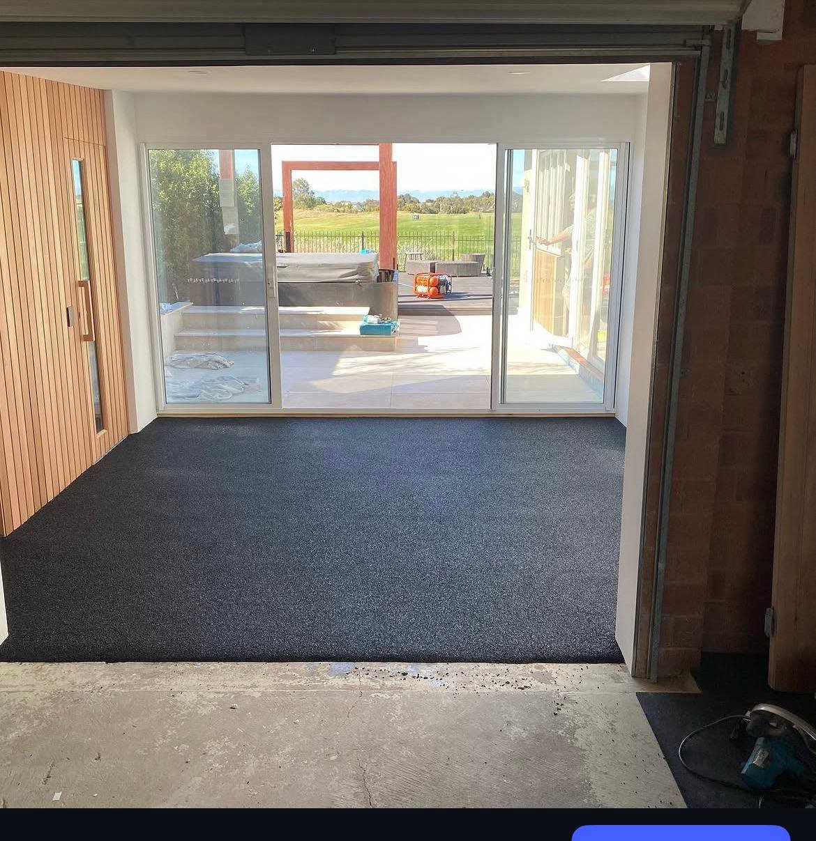Charcoal poured rubber gym floor in a home studio opening onto a deck